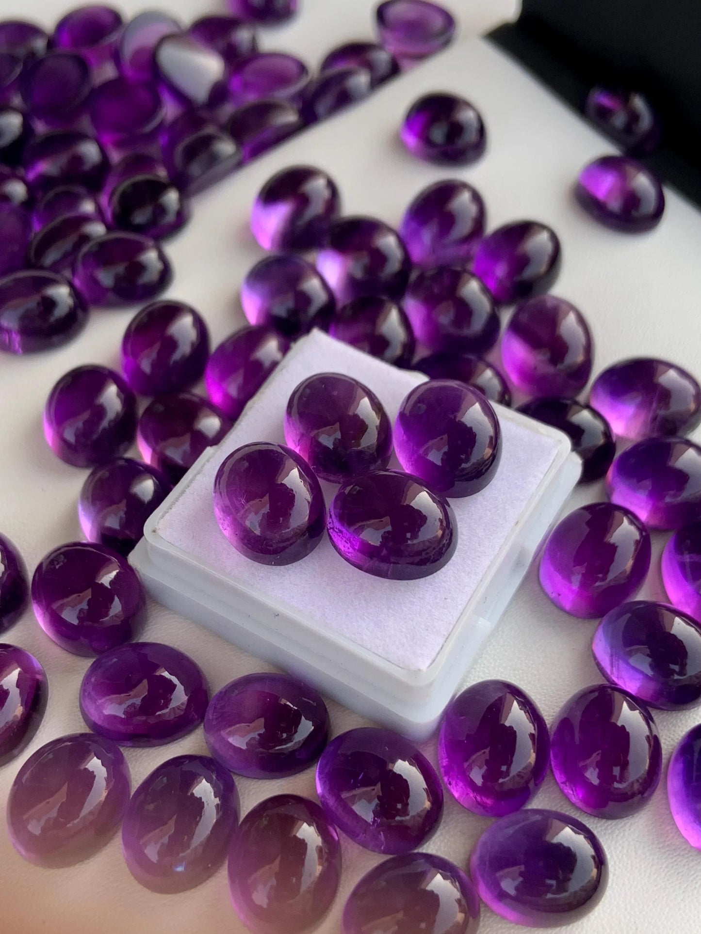 Polished oval amethyst cabochon gemstones on white background