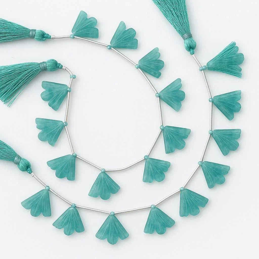 Carved fan-shaped teal gemstone beads with tassels on a string, jewelry making supplies.