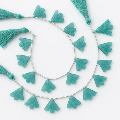 Carved fan-shaped teal gemstone beads with tassels on a string, jewelry making supplies.