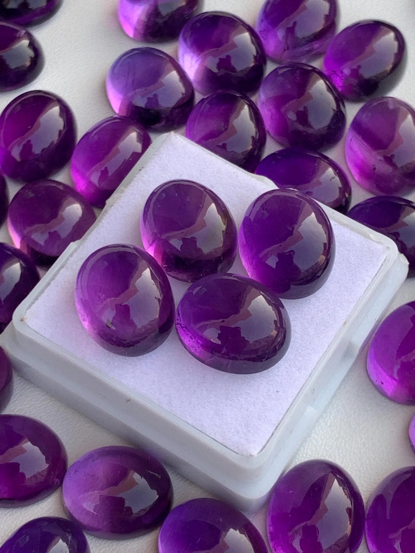 Polished amethyst cabochon gemstones displayed on white background for jewelry making
