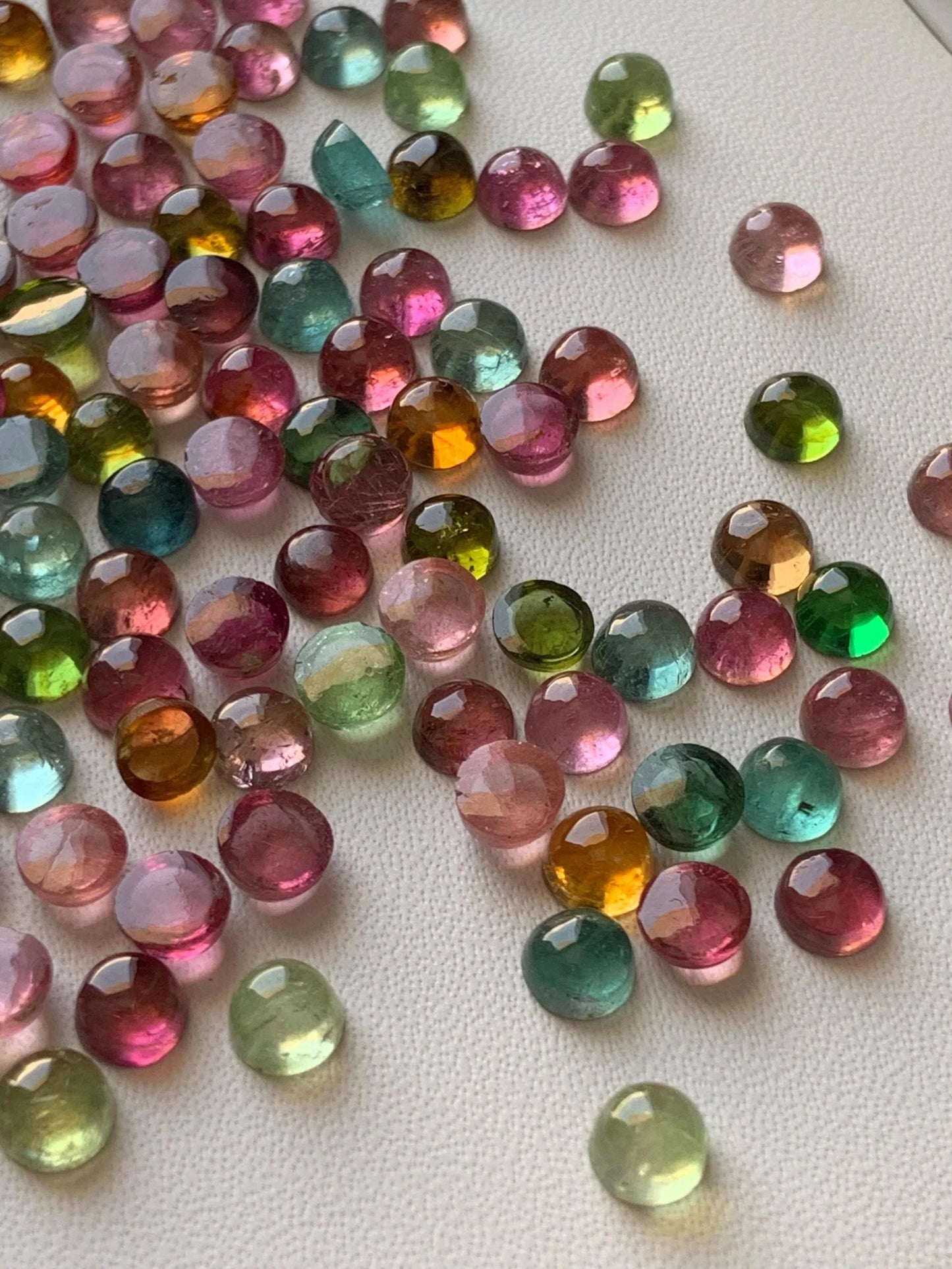 Mixed color faceted round tourmaline cabochon gemstones on white background