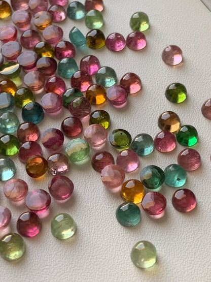 Mixed color faceted round tourmaline cabochon gemstones on white background