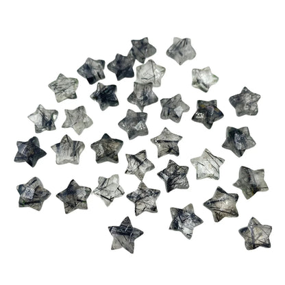 Star-shaped rutilated quartz gemstone beads scattered on a white background