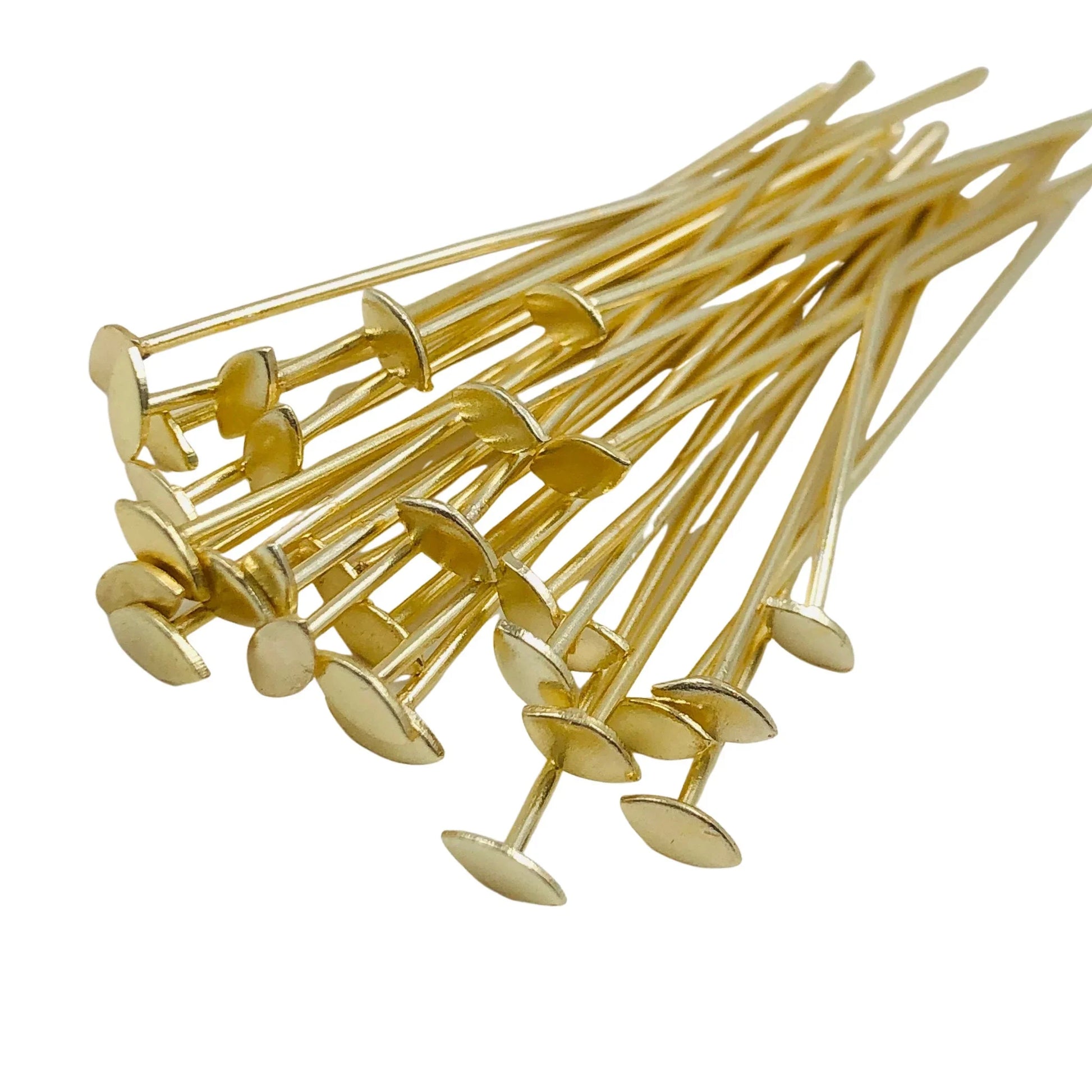 Gold-plated flat head pins for jewelry making or beading, clustered on a white background