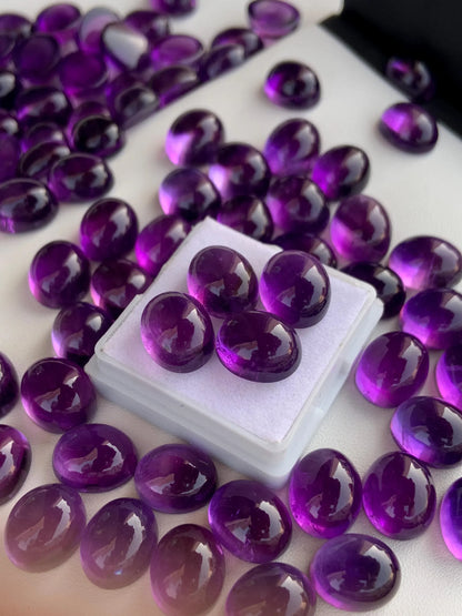Polished oval amethyst cabochon gemstones on white background