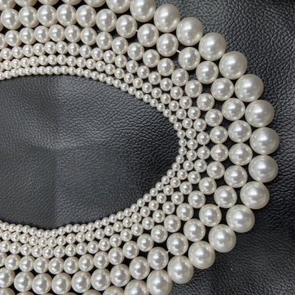 multiple strands of round white pearl beads on black textured background