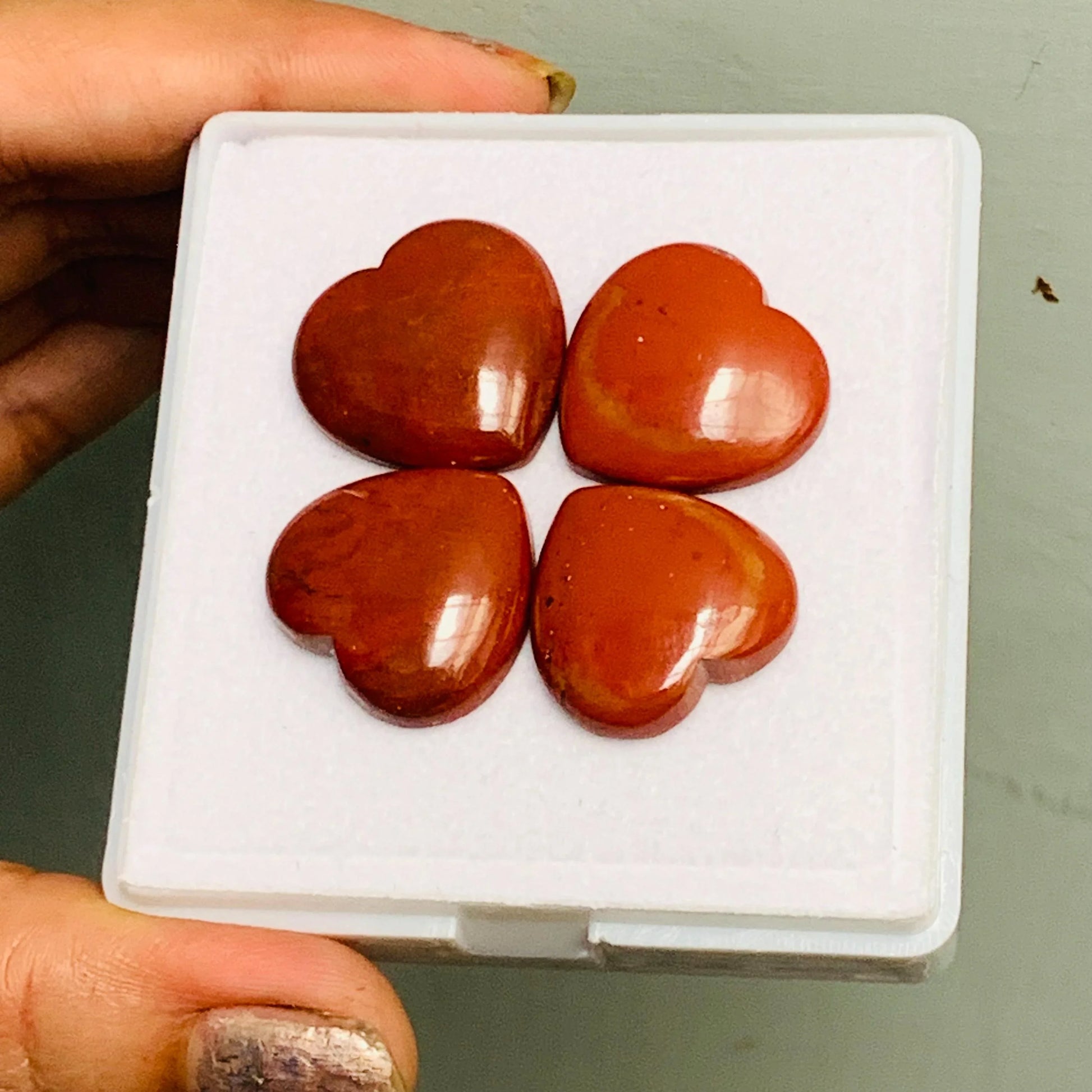 Four polished red jasper heart cabochon gemstones in display box
