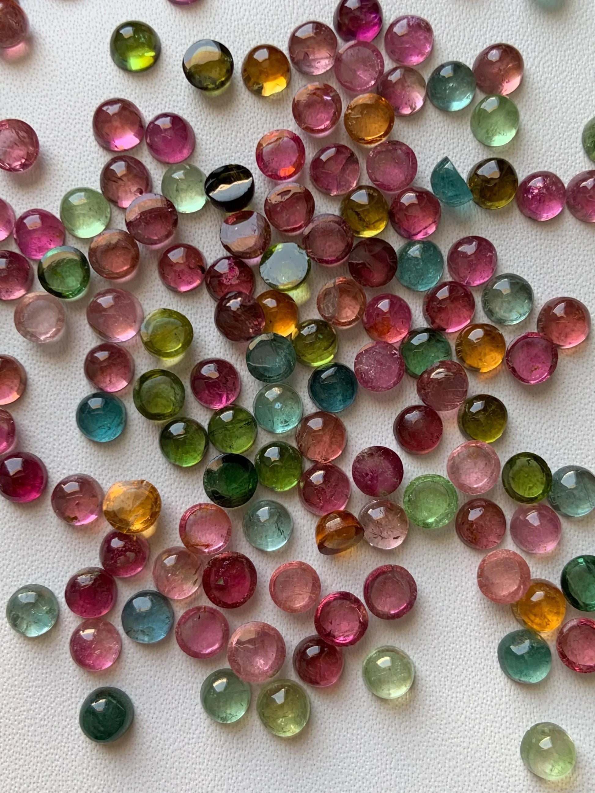Mixed color round natural tourmaline cabochon beads on white background