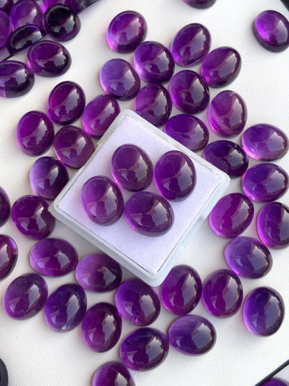 Oval polished amethyst cabochon loose gemstones with deep purple color on white background