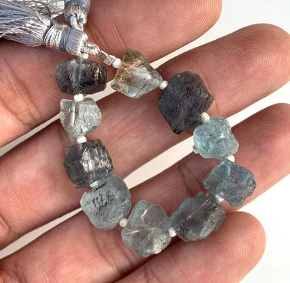 Natural rough aquamarine gemstone beads strand with tassels, held in hand