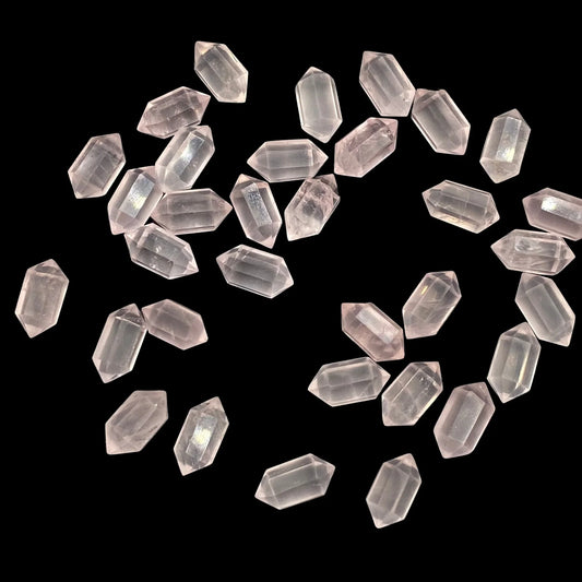 Loose hexagonal rose quartz gemstone beads on black background