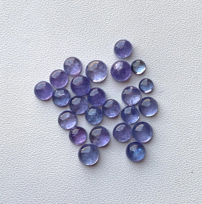 Round faceted natural iolite cabochon gemstones on white textured background