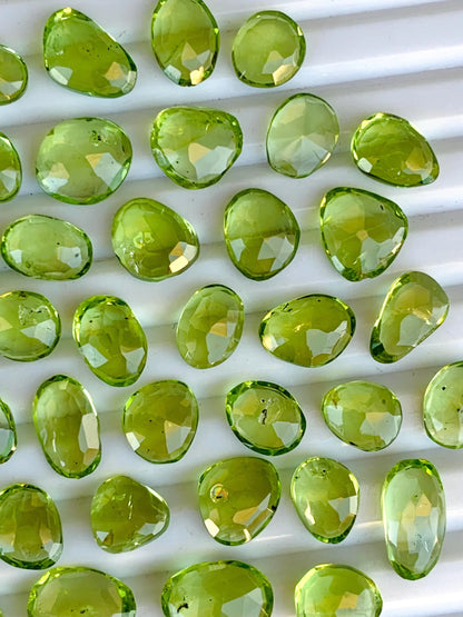 Faceted green peridot gemstone beads arranged on a white background
