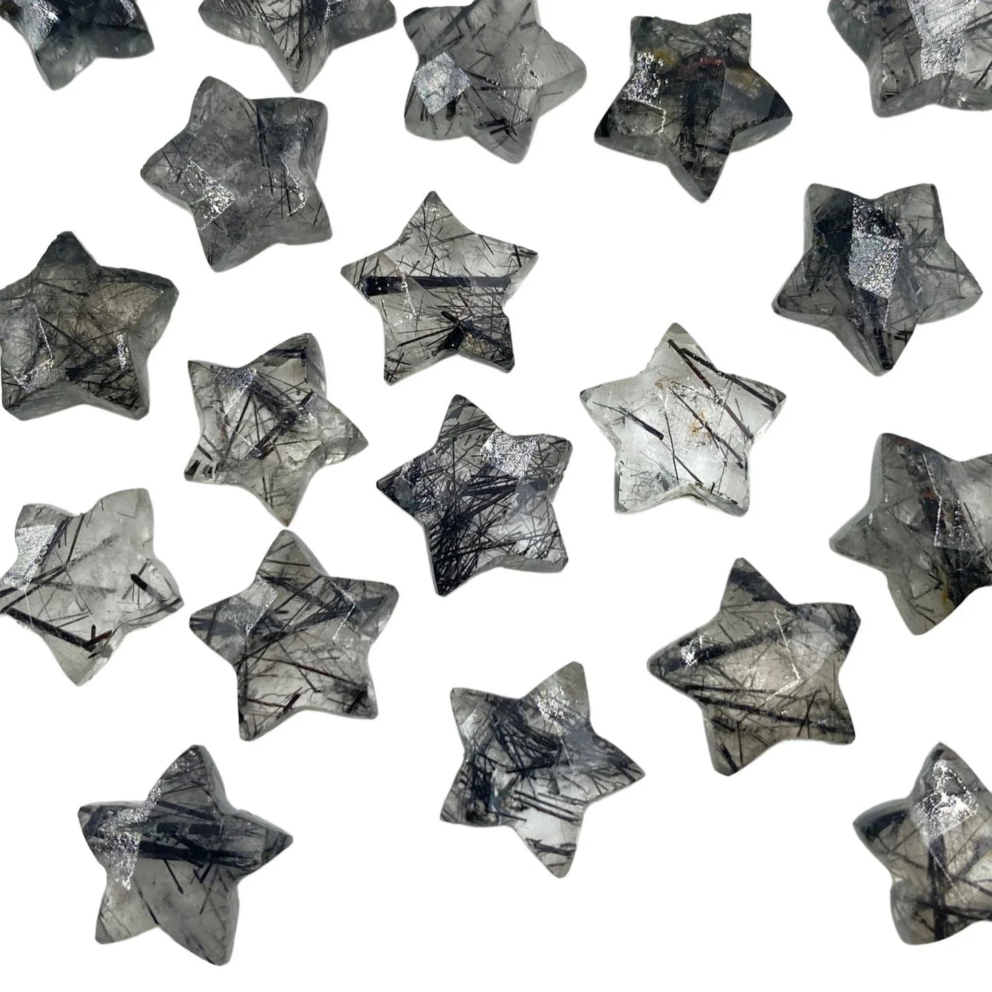 Star-shaped rutilated quartz gemstone beads scattered on a white background