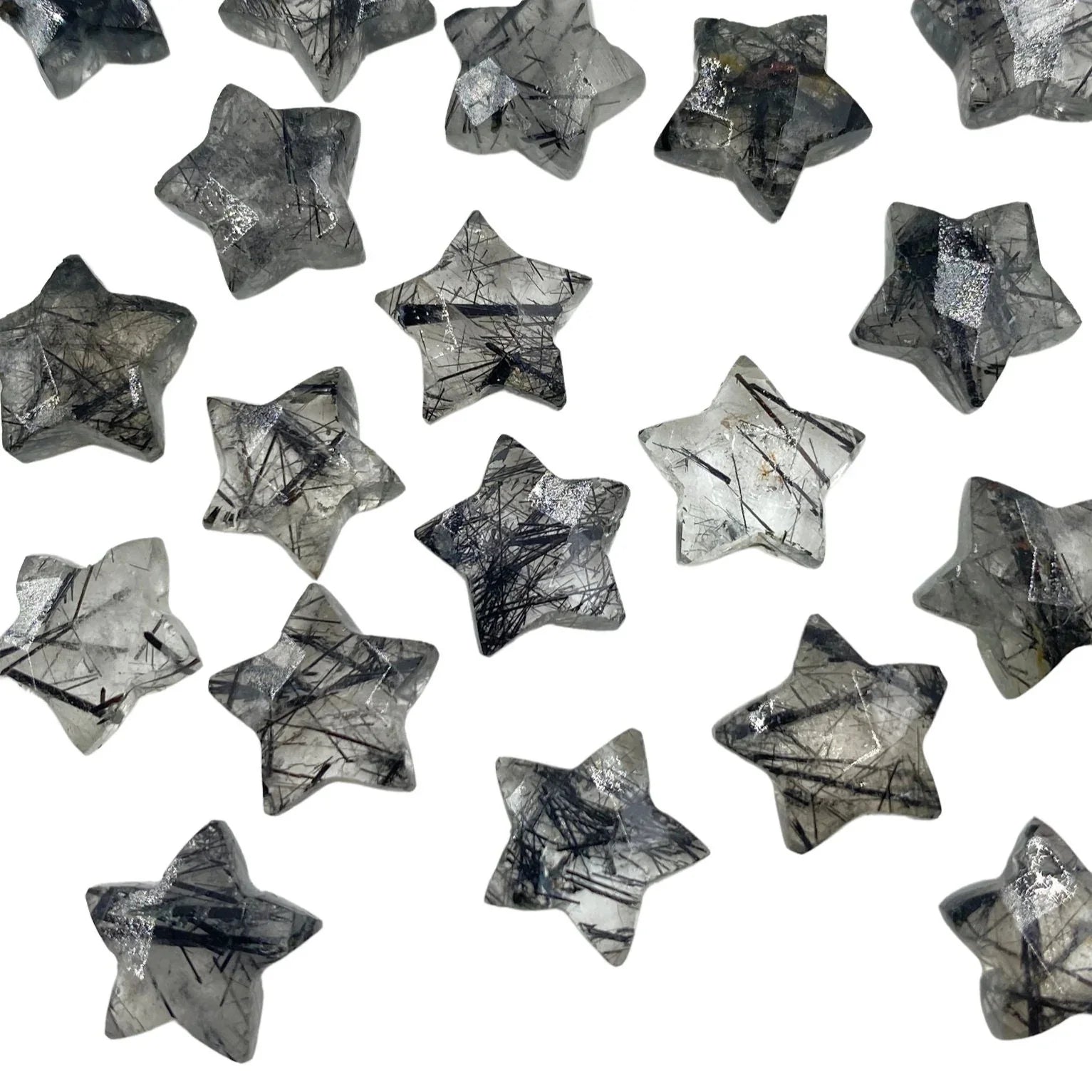 Star-shaped rutilated quartz gemstone beads scattered on a white background