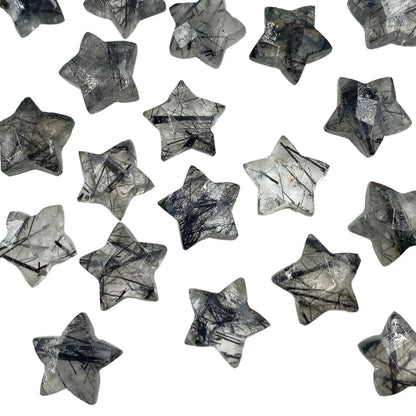 Star-shaped rutilated quartz gemstone beads scattered on a white background