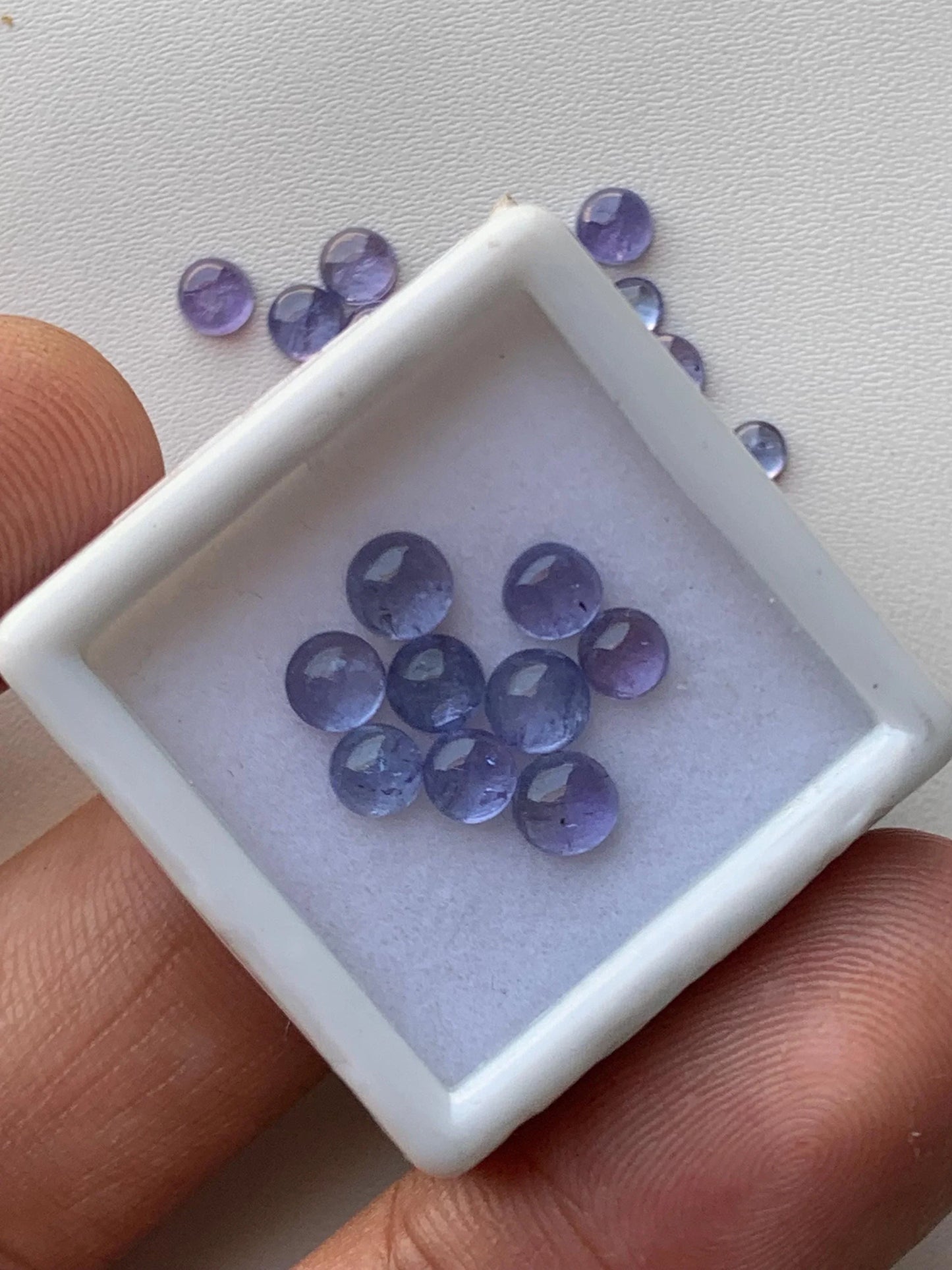 Round natural purple gemstone cabochon beads displayed in a white jewelry tray