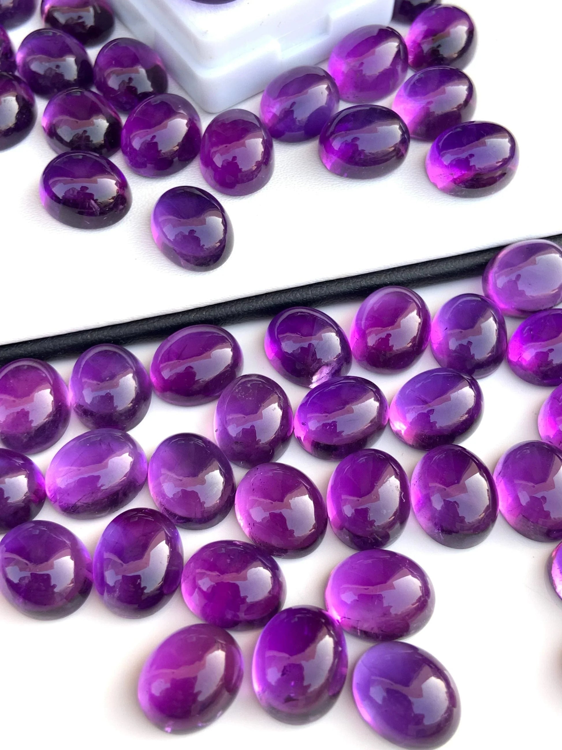 Oval-shaped polished purple gemstone cabochons on a white background.
