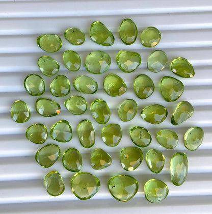 Faceted pear-shaped green peridot gemstone beads arranged on a white background