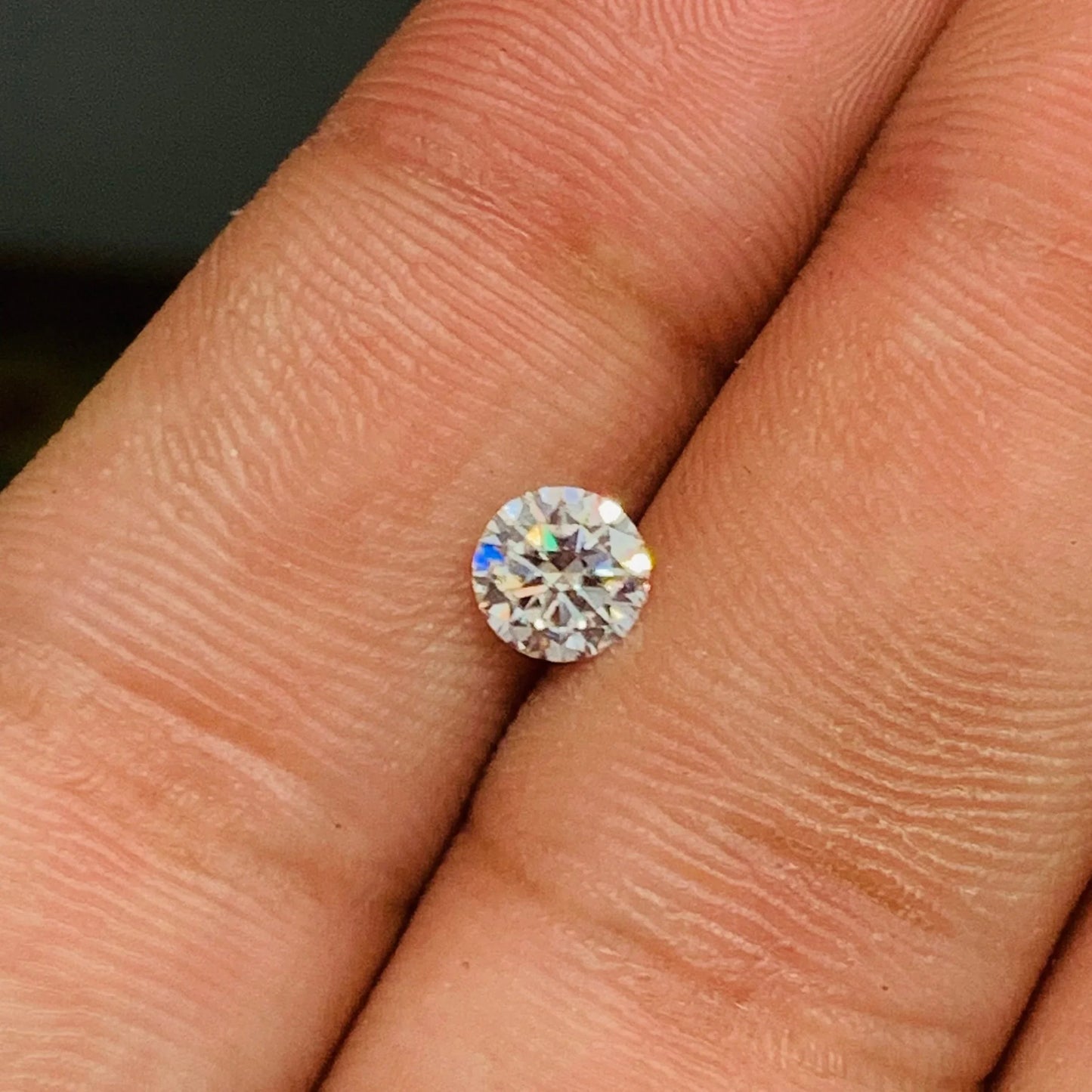 Round brilliant cut gemstone on fingertip, loose natural stone with sparkling facets