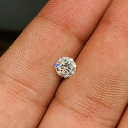 Round brilliant cut gemstone on fingertip, loose natural stone with sparkling facets