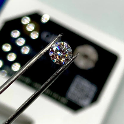 Round brilliant cut gemstone held by tweezers, loose natural stone for jewelry making