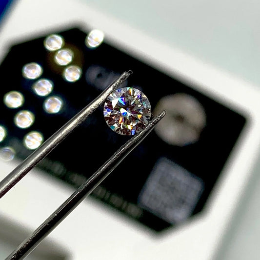 Round brilliant cut gemstone held by tweezers, loose natural stone for jewelry making