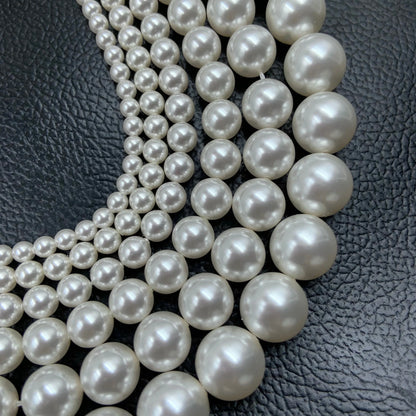 Strands of round white gemstone beads arranged on black textured leather