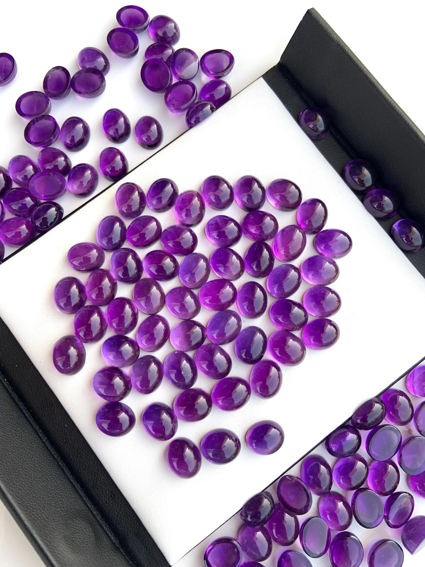 Oval purple amethyst cabochon gemstones displayed on white background