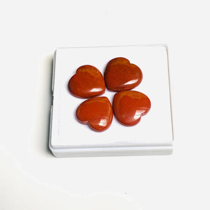 Four heart-shaped red jasper gemstone cabochons on a white display box