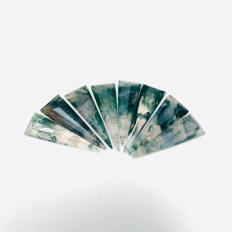 A set of seven polished triangular stone slices fanned out on a plain white background. The stones display a marbled pattern of dark green, teal, gray, and off-white.